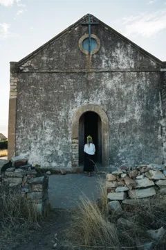 A person standing in the arched doorway of the original Nieuwoudtville church
