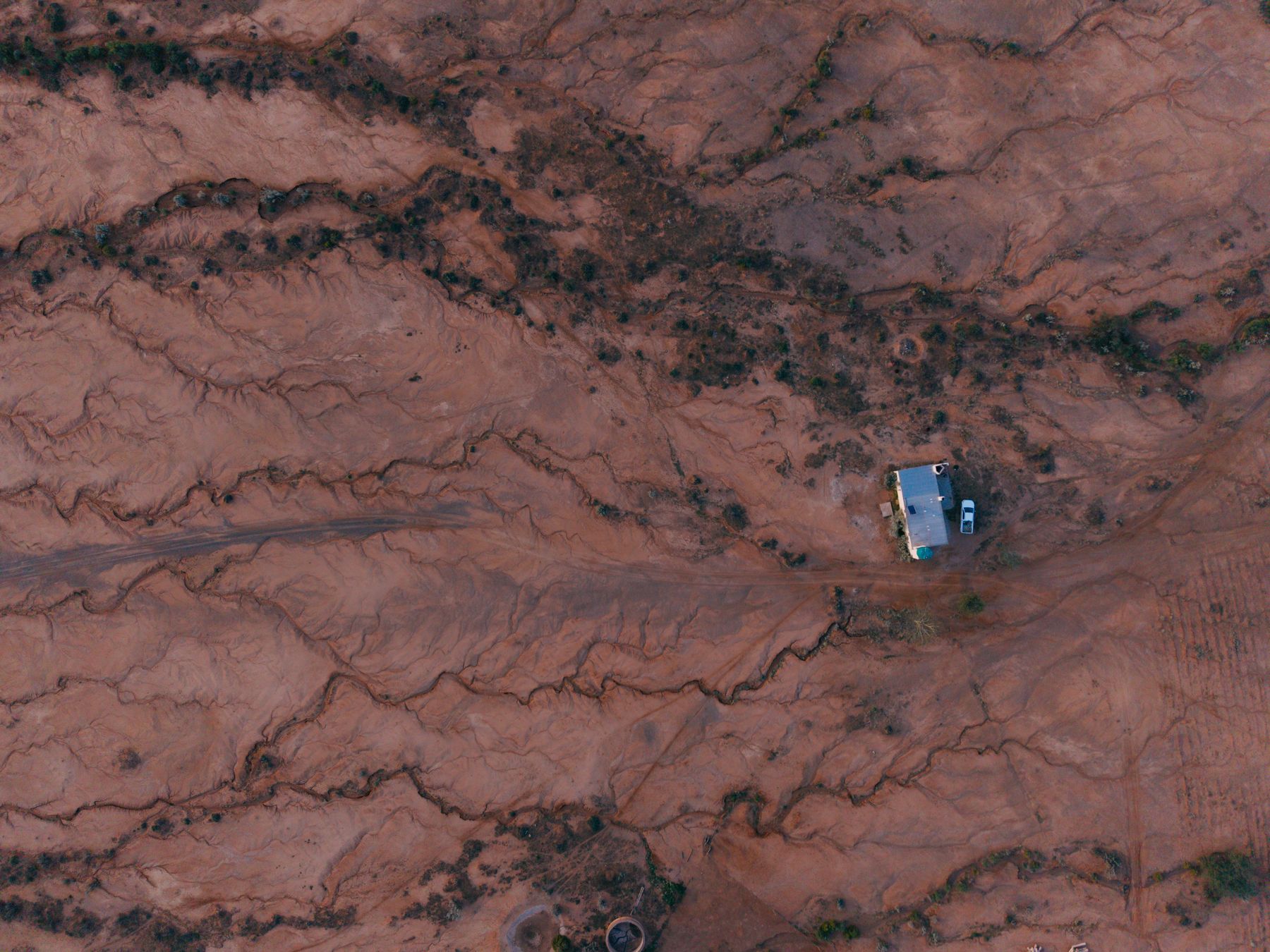 Aerial view of drainage lines in red earth with a vehicle for scale
