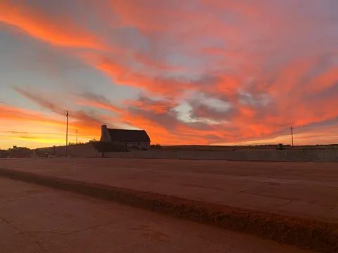 A red dirt road across the plateau under an evening sky